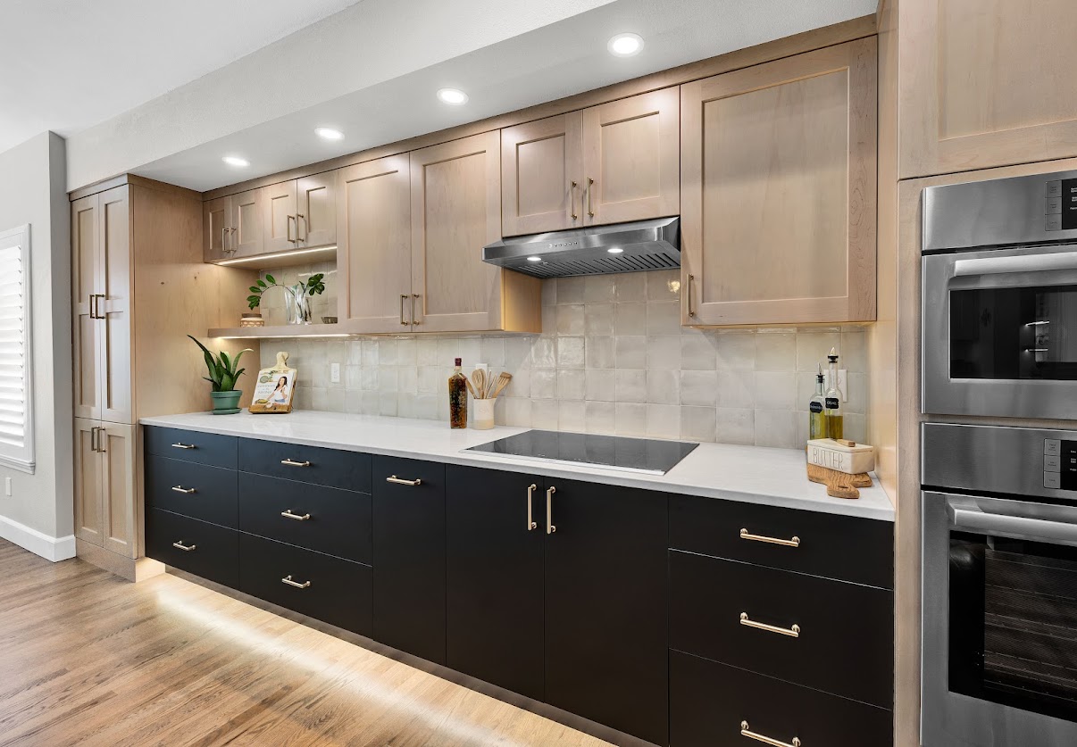 Kitchen cabinetry with lit display shelf and under-cabinet lights above cooktop