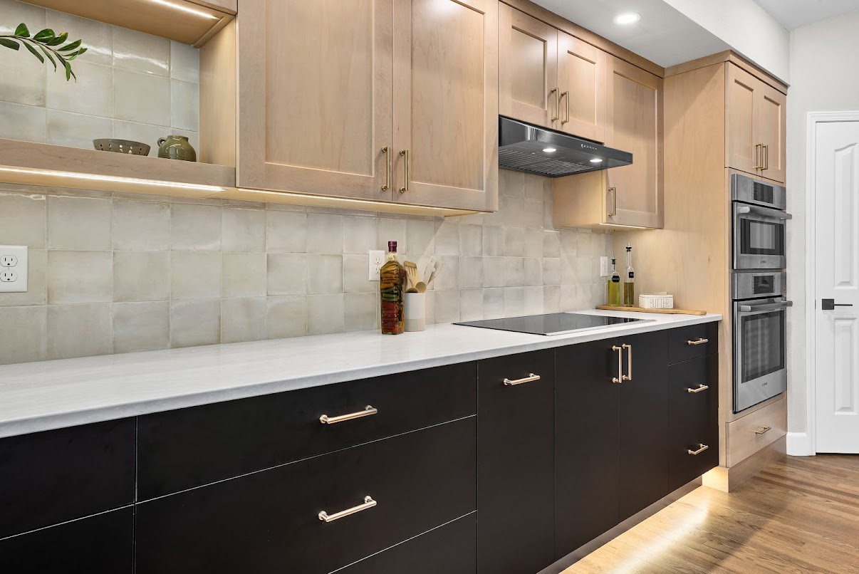 Light wood and dark cabinet kitchen with lit cooking wall and recessed lights