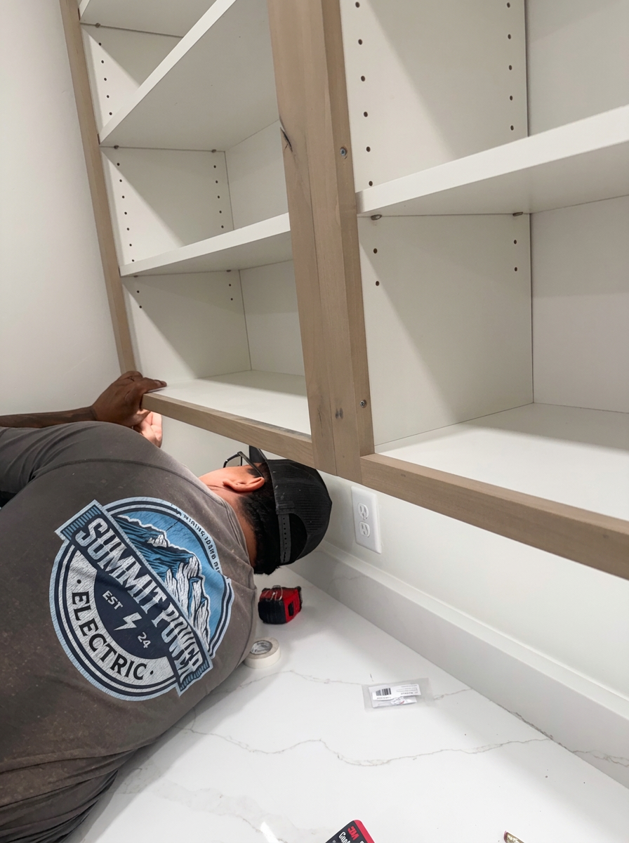 Summit Power Electric electrician completing finish work beside custom cabinetry